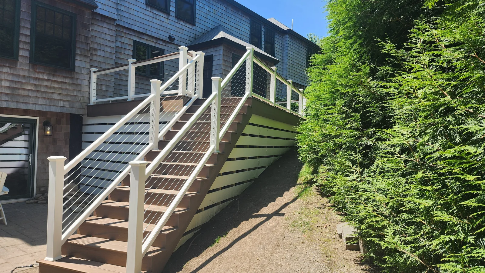Exterior deck staircase with white posts and cable railing