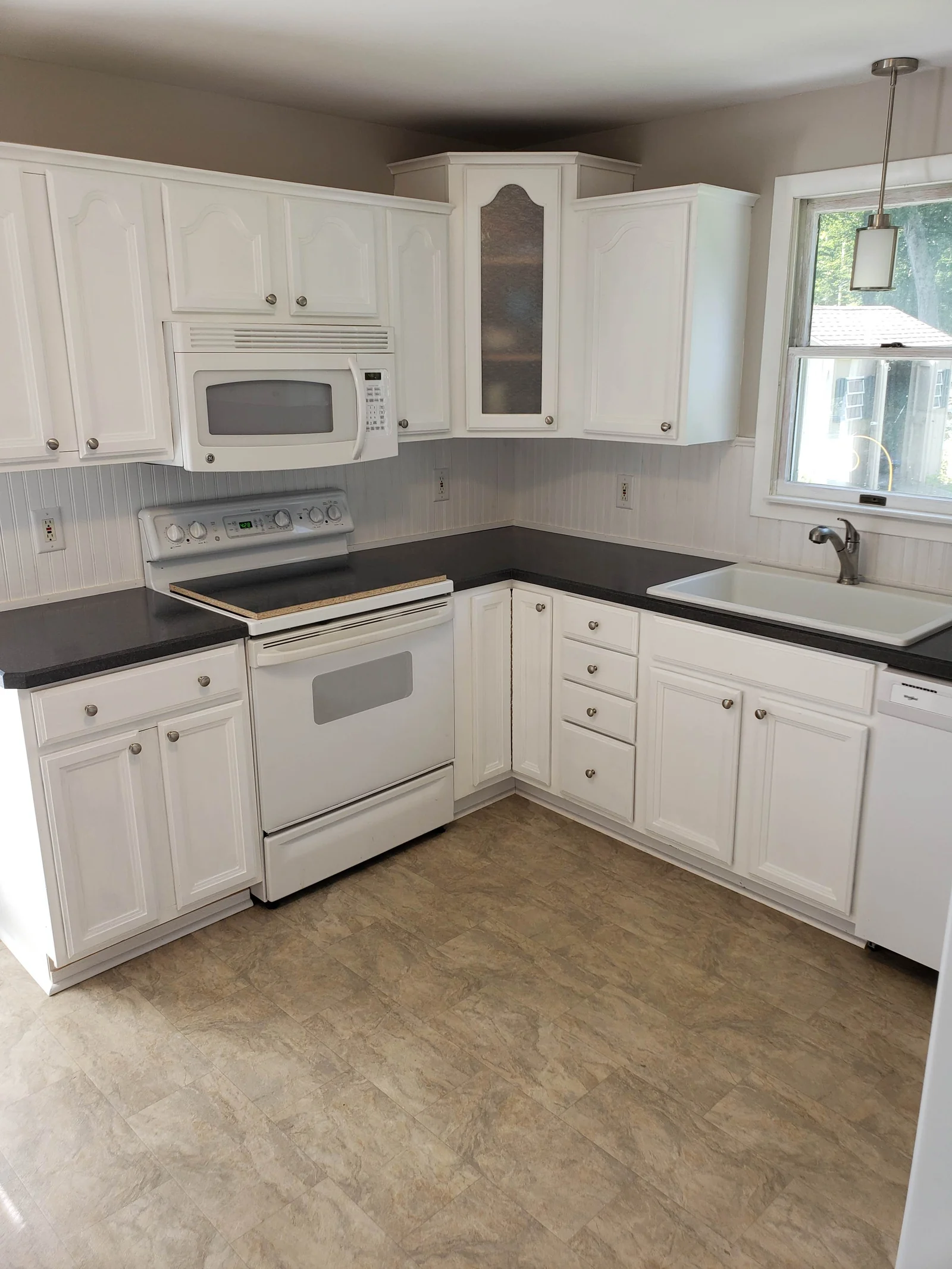 White kitchen cabinets, dark countertops, and a sink by the window